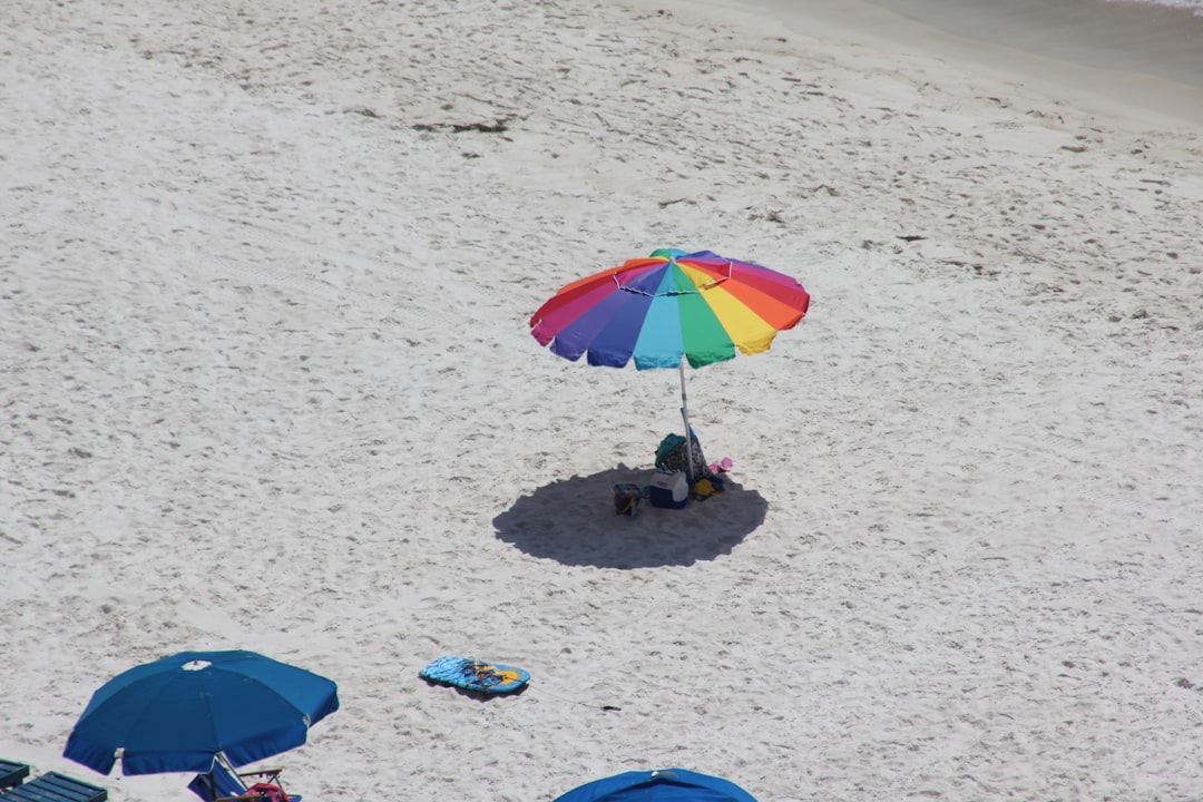 families walking on sandy beach with colorful umbrellas