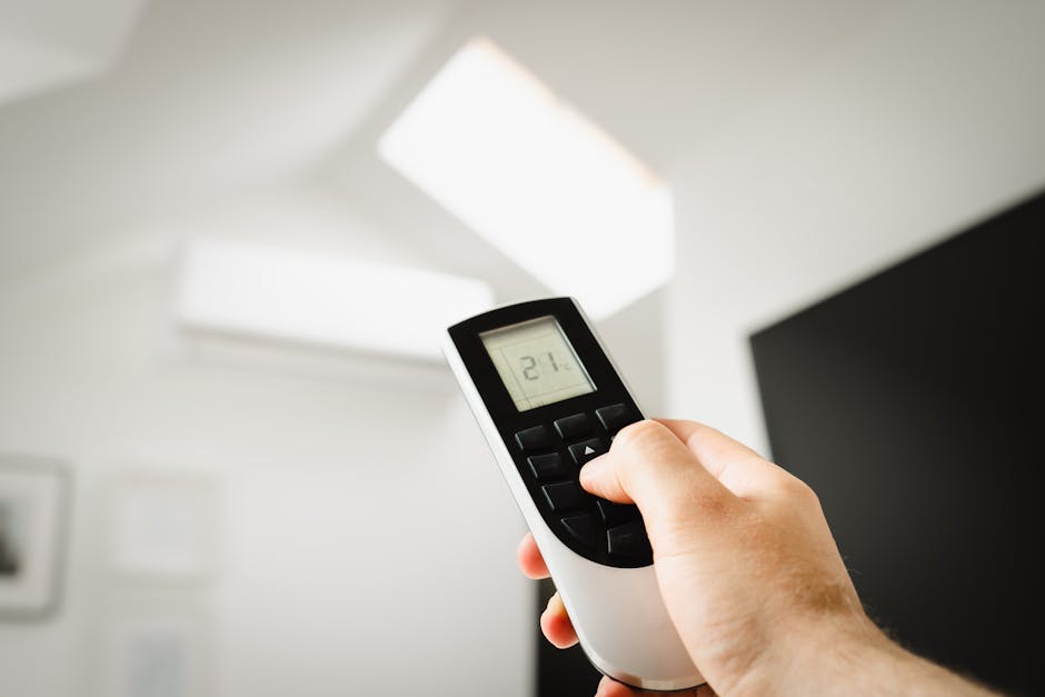 hand adjusting temperature control on wall-mounted air conditioner remote control