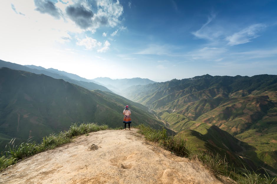 hiker standing on mountain ridge looking at green valleys