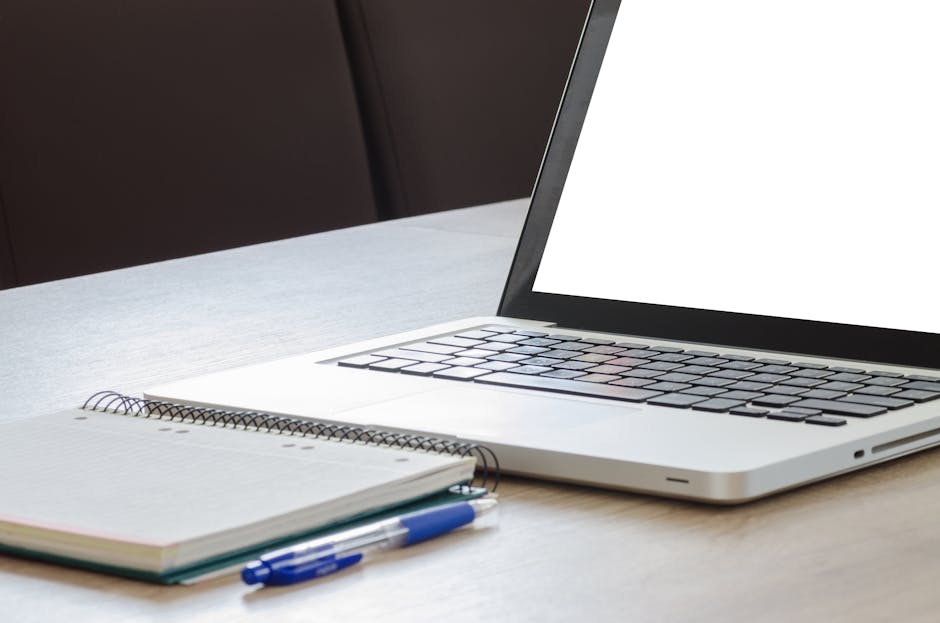 modern laptop on wooden desk with notebook