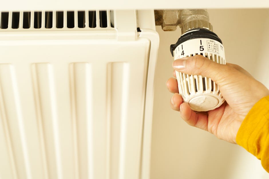 person adjusting smart thermostat on wall radiator