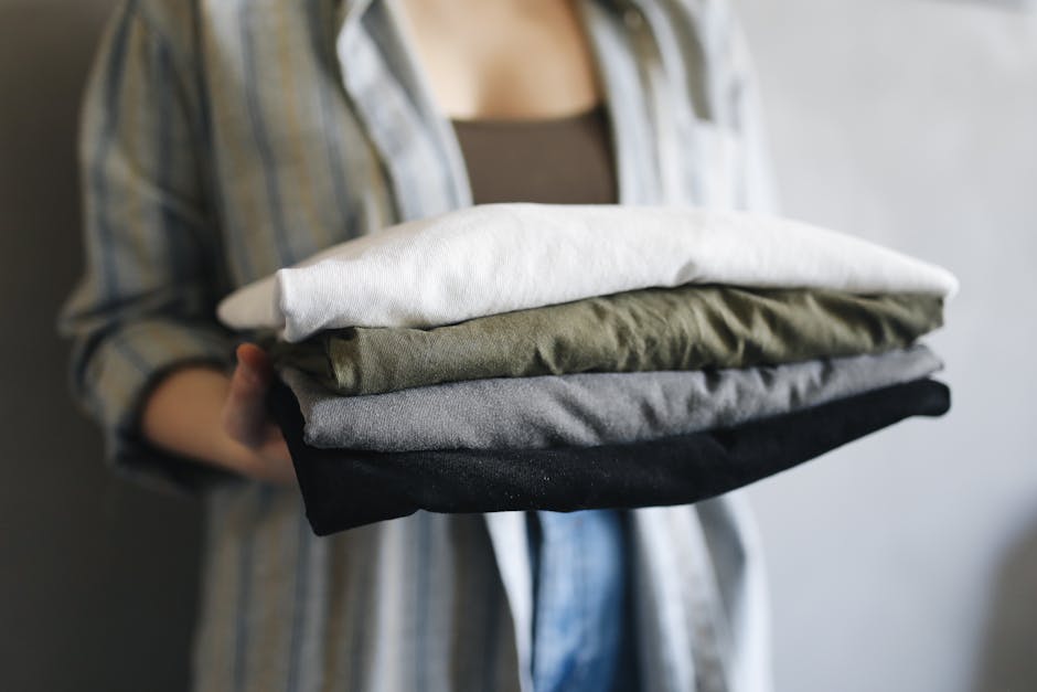 person folding colorful clothes in bright room