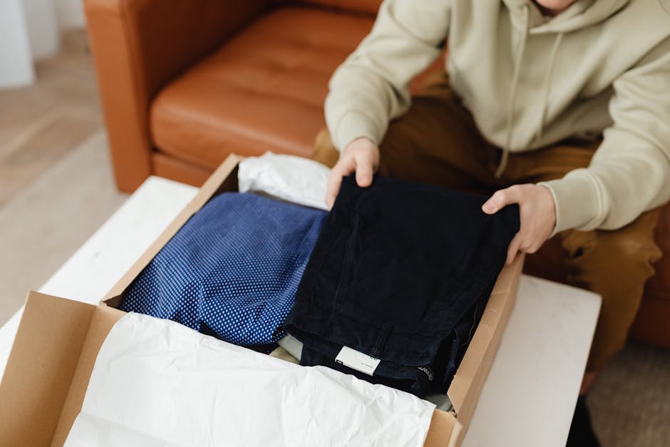 person holding opened delivery box with new clothing items