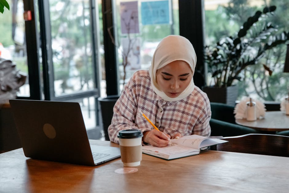 student with laptop studying at coffee shop table